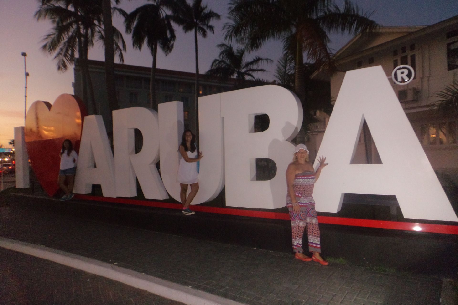 Chicas posando en Letrero de Aruba, La isla feliz